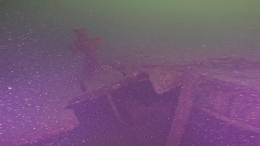 Underwater wreckage and debris resting on a barren lakebed